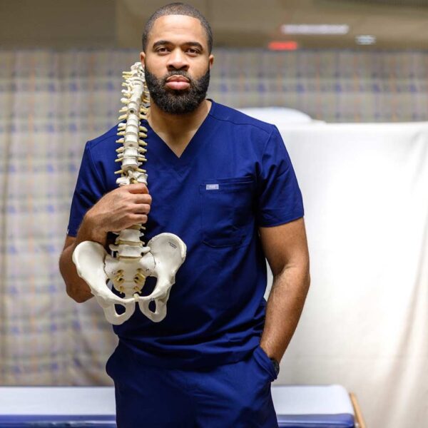 Dr. Nduka Unaka holding skeletal model of spine and hip