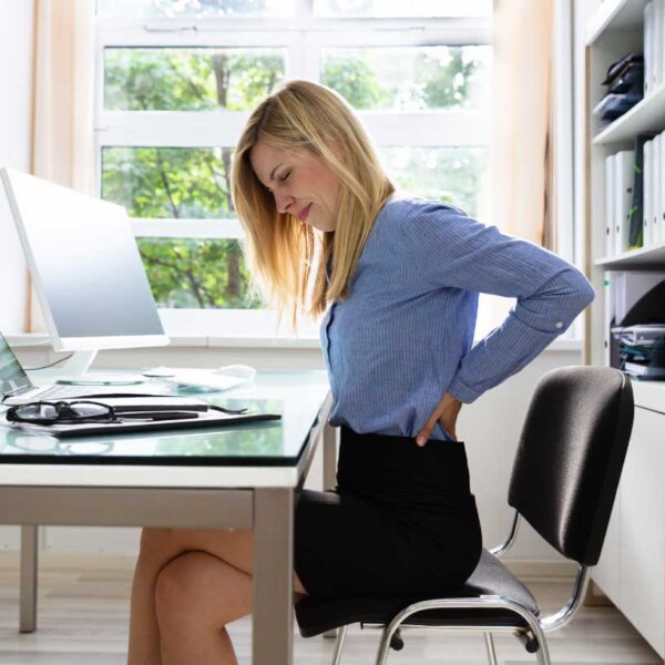 Woman sitting at desk holding her lower back